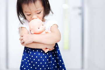 Little baby child holding baby doll afraid to walk out the door