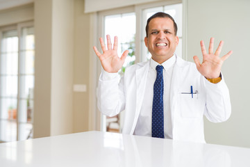 Middle age doctor man wearing medical coat at the clinic showing and pointing up with fingers number ten while smiling confident and happy.