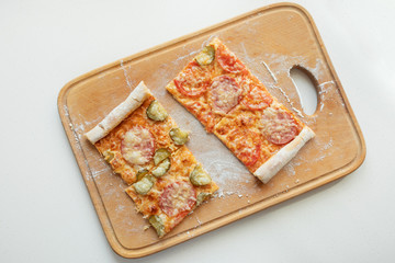 Pizza with mozzarella cheese, salami, tomatoes and spices. Italian pizza on a wooden board. Close-up