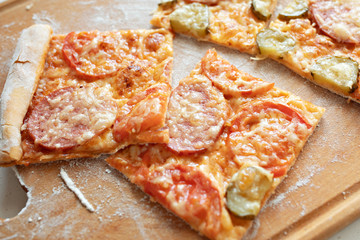 Pizza with mozzarella cheese, salami, tomatoes and spices. Italian pizza on a wooden board. Close-up