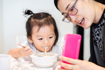 Aunty showing smartphone for little baby child for talking with her father during her breakfast
