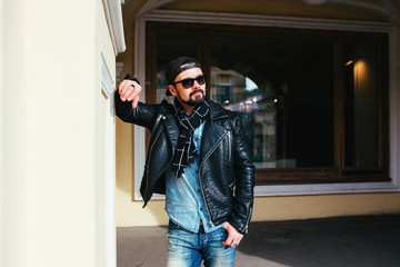 Fototapeta na wymiar Man in leather jacket and eyeglasses posing in city