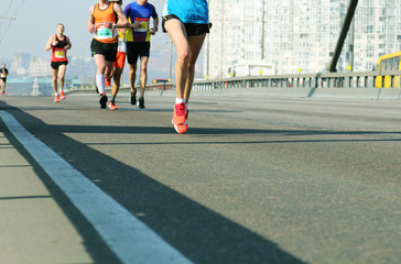 Young woman running on city bridge road. Female leader athlete runner running city marathon. Marathon running in the morning