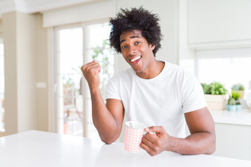 African American man with afro hair drinking a cup of coffee screaming proud and celebrating victory and success very excited, cheering emotion