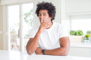 Fototapeta na wymiar Young african american man wearing casual white t-shirt sitting at home asking to be quiet with finger on lips. Silence and secret concept.