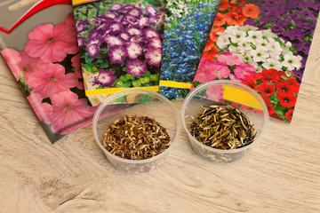 Seeds of annual flowers in bags and in bulk in jars lie on a wooden surface