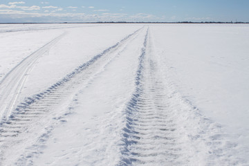 Fototapeta na wymiar winter landscape wheel print in the snow, going beyond the horizon