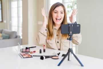 Beautiful young influencer woman recording make up video tutorial celebrating mad and crazy for...