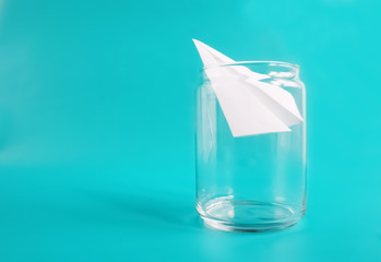Freedom and dreams concept. Paper plane in jar. Isolated on blue background.