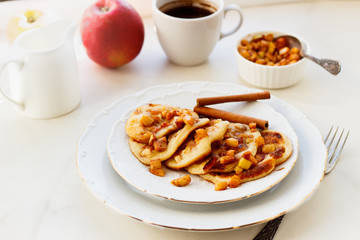 Stack of pancakes with honey and apple on white table, delicious dessert for breakfast.