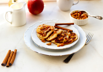Stack of pancakes with honey and apple on white table, delicious dessert for breakfast.