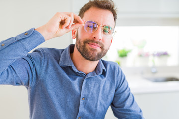Obraz premium Handsome man wearing glasses and smiling relaxed at camera