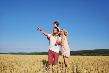 A happy family standing in a wheat field.