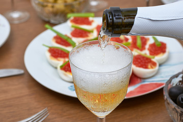 Pouring champagne into the glass from the bottle, close-up