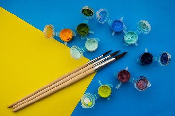 Flat lay composition with different acrilic or oil paints and brushes on grunge background.