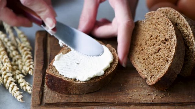 Closeup view of spreading cream cheese on rye bread