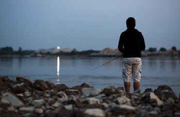 Fisherman.  Young man fishing on the river.