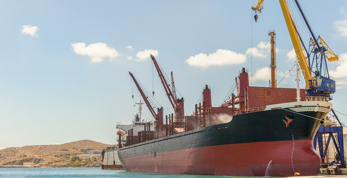 Bulk Carrier . Isolated. Big bulk carrier with heavy lifts moored in harbour. Stock Image.