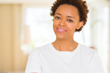 Young beautiful african american woman wearing casual white t-shirt happy face smiling with crossed arms looking at the camera. Positive person.