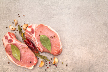 Raw pork steak with spices and dried herbs. Salt, garlic, hot pepper, rosemary, bay leaf on a stone...