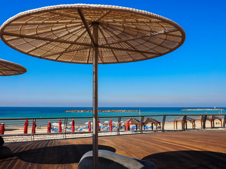 Straw sunshades in sunny summer day in the beach Tel Baruch in Tel Aviv, Israel.