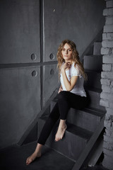 Fototapeta na wymiar Beautiful girl sitting on the background of a concrete wall
