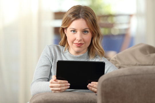 Beauty woman looking at camera holding tablet at home