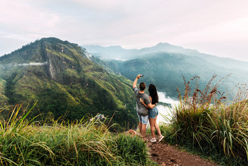 A couple in love takes a selfie. Man and woman holding hands. The couple travels around Asia. Travel to Sri Lanka. Honeymoon trip. Wedding travel. Tourists in the mountains. Dawn in the mountains