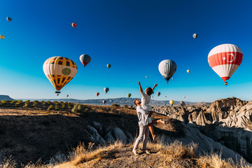 Couple in love among balloons. A guy proposes to a girl. Couple in love in Cappadocia. Couple in Turkey. Honeymoon in the mountains. Man and woman traveling. Flying on balloons. Wedding. Journey. Love