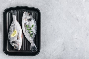 Fresh raw dorado fish with spices. Ingredients for cooking in cast iron grill pan.