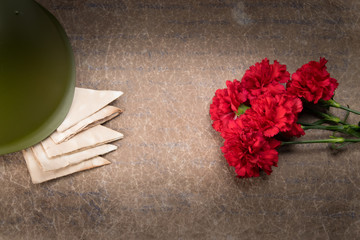 on old paper, a bouquet of red carnations, envelopes and a military helmet