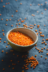 Red lentils in a bowl close up on dark stone background