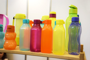 Obraz na płótnie Canvas Group of empty sports water bottles of different colors and shapes on white background. Bright empty polyethylene bottles and tableware for fresh drinks.