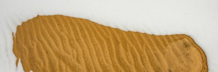 wet sand in snow covered dunes. Web banner.