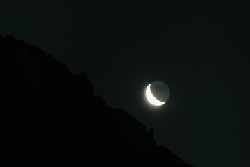 Naklejka na ściany i meble Moon besides the Girnar mountain located in Gujarat, India during night 