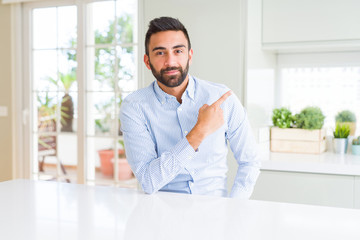 Fototapeta premium Handsome hispanic business man Pointing with hand finger to the side showing advertisement, serious and calm face