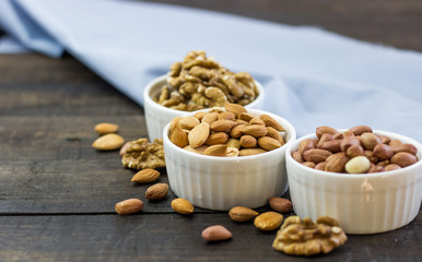 Tasty nuts arrangement in a bowl on a wooden table. Healthy food and snack, organic vegetarian food. Walnut, almond, peanut