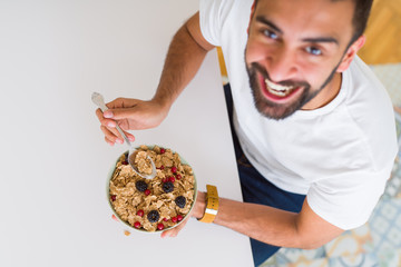 Above angle of handsome man eating healthy cereals for breakfast in the morning