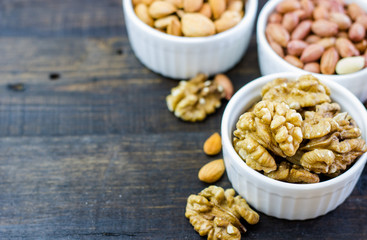 Tasty nuts arrangement in a bowl on a wooden table. Healthy food and snack, organic vegetarian food. Walnut, almond, peanut