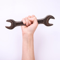 A wrench in the hand of a girl. Symbol of hard work, feminism and labor day. Isolate on white background.