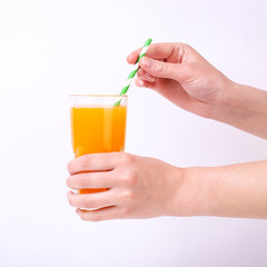 A glass with orange juice and a straw in hand in the girls. Isolate on white background.