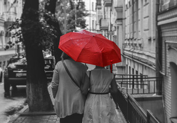 people walk under an umbrella in the rain down the old street in black and white style