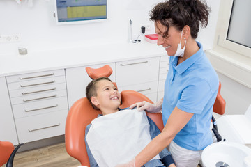 Junge auf dem Zahnarztstuhl, lächelt entspannt zur Assistentin