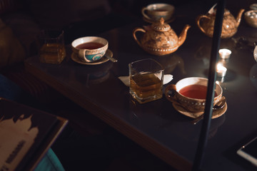 Hookah, making clouds, Arabian interior. a cup of tea and sugar cubes with different tastes, handmade, a smartphone on the table, eastern tea ceremony. dark. Selective focus, copy space