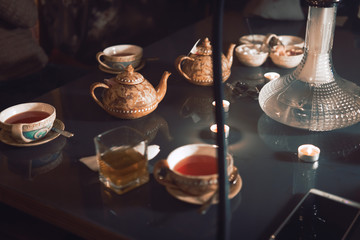 Hookah, making clouds, Arabian interior. a cup of tea and sugar cubes with different tastes, handmade, a smartphone on the table, eastern tea ceremony. dark. Selective focus, copy space