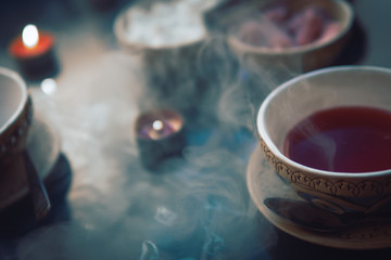 a cup of red tea and sugar cubes with different tastes, handmade, on the glass table, eastern tea ceremony. dark. Selective focus, copy space, Hookah concept, making clouds, Arabian interior.