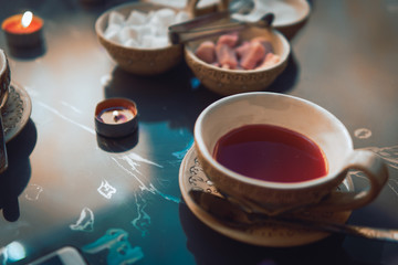 a cup of red tea and sugar cubes with different tastes, handmade, on the glass table, eastern tea ceremony. dark. Selective focus, copy space, Hookah concept, making clouds, Arabian interior.