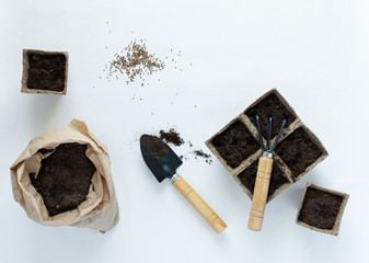 Eco friendly pots for seedlings and seeds on white background, small bag with ground and garden...