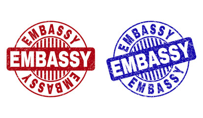 Grunge EMBASSY round stamp seals isolated on a white background. Round seals with grunge texture in red and blue colors. Vector rubber imprint of EMBASSY label inside circle form with stripes.