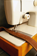 Background type of sewing machine, leather belt sewing process. Leather workshop.